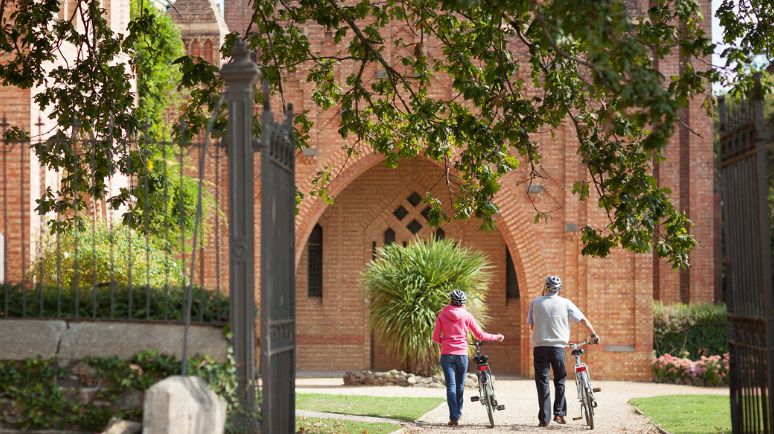 A couple walk their bikes into the grounds of Quarr Abbey, Isle of Wight