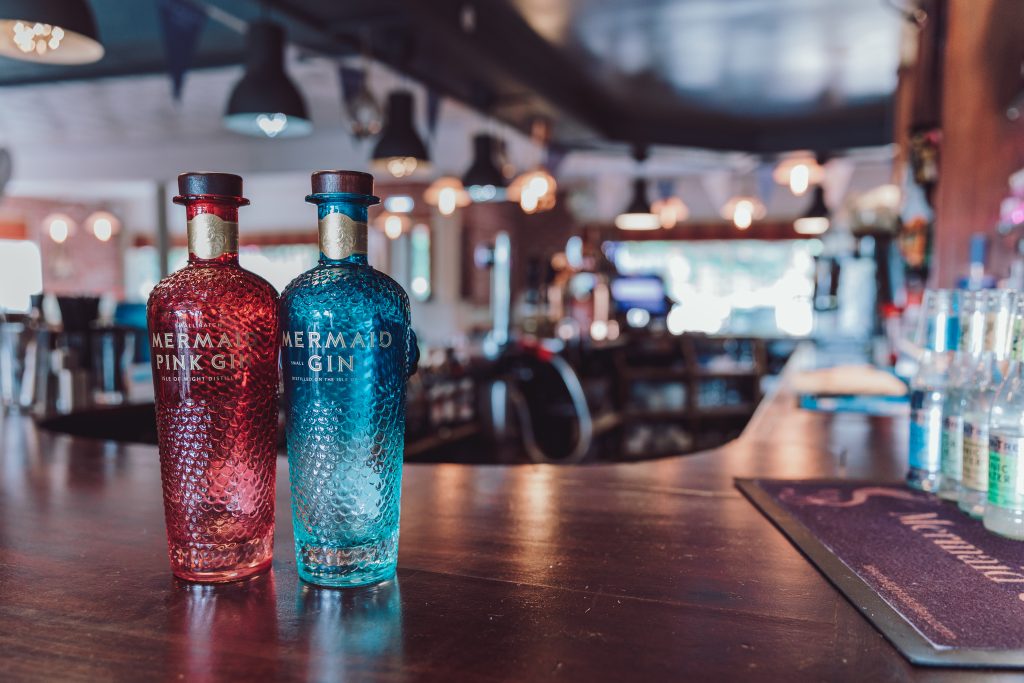 Two bottles of Mermaid Gin - one pink, one blue - on a bar at the Isle of Wight Distillery