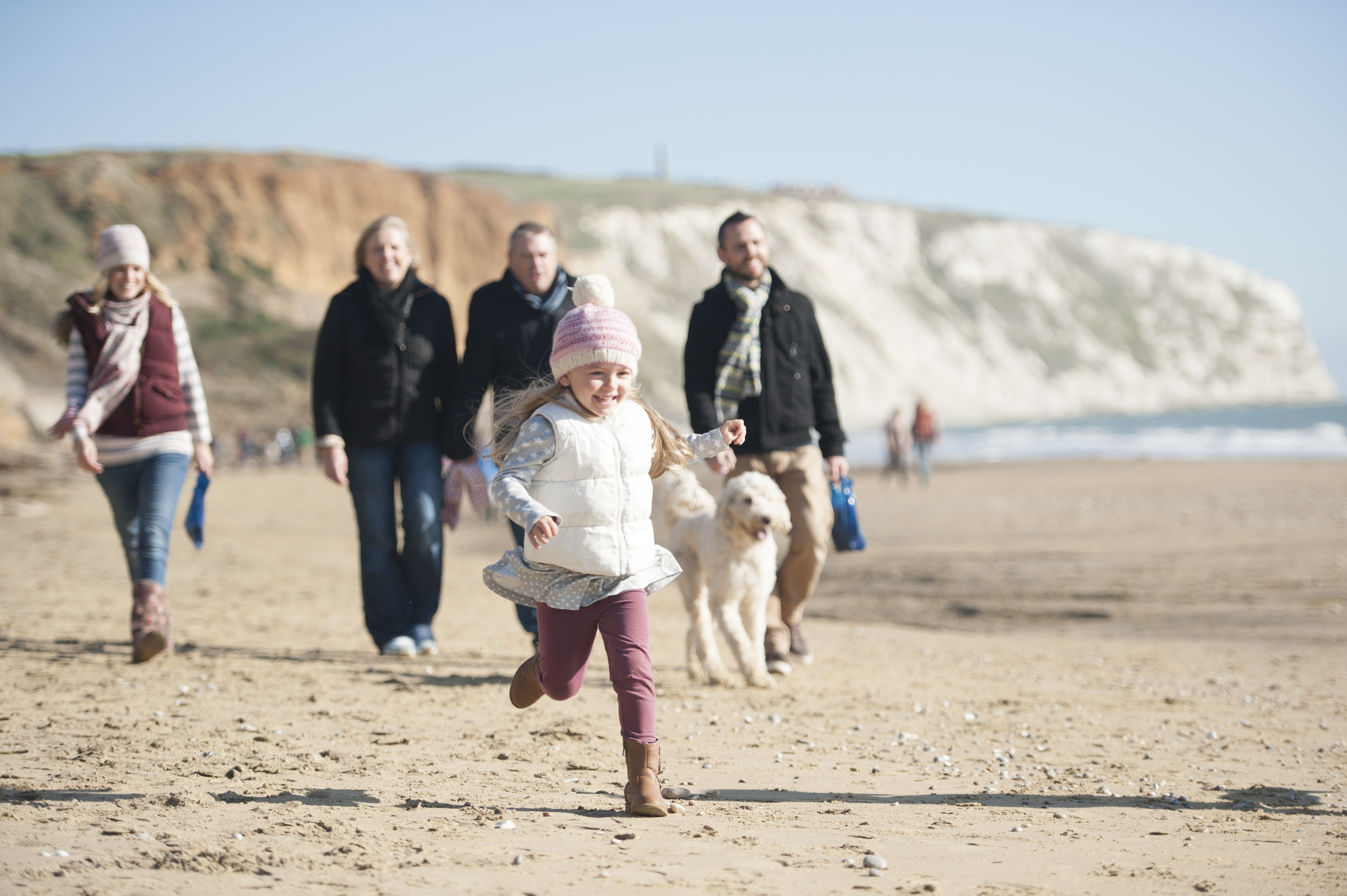 A family and their dog walking along the beach at Alum Bay, Isle of Wight