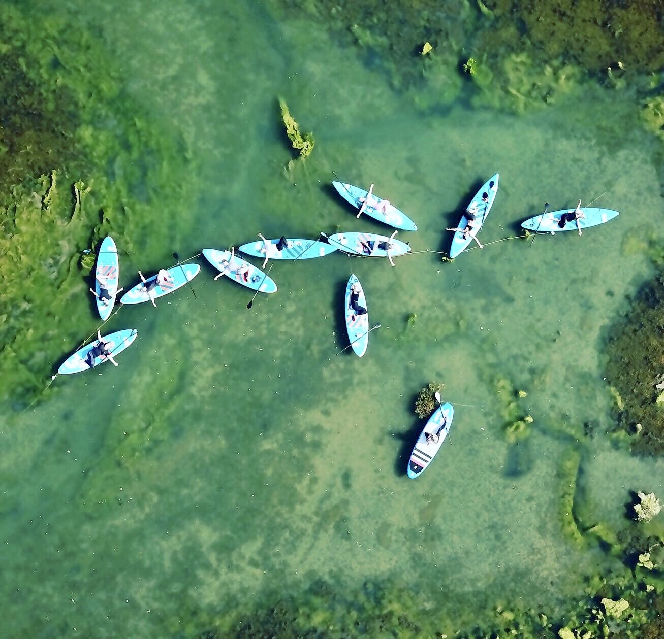 An aerial photo of people doing stand up paddleboard yoga on the River Yar on the Isle of Wight
