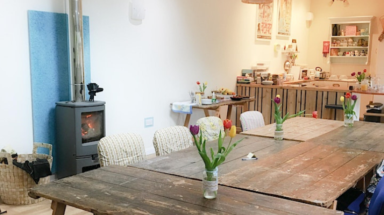 Tables in a workshop space with a kitchen and wood burner, and tulips on the tables