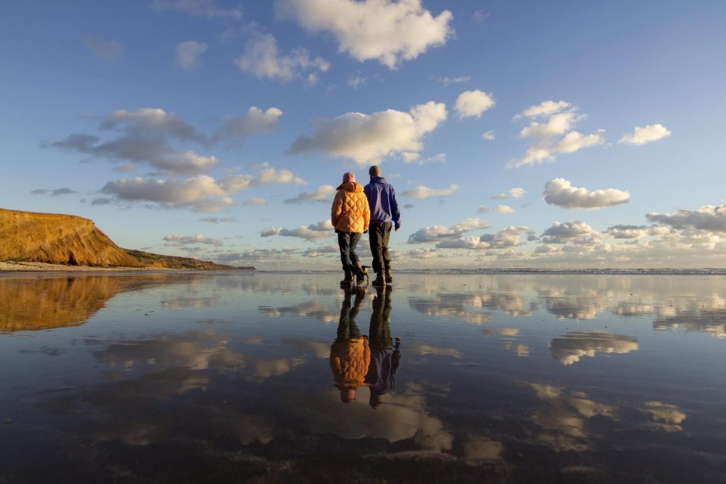 A couple walking along the beach wearing winter clothes on the Isle of Wight