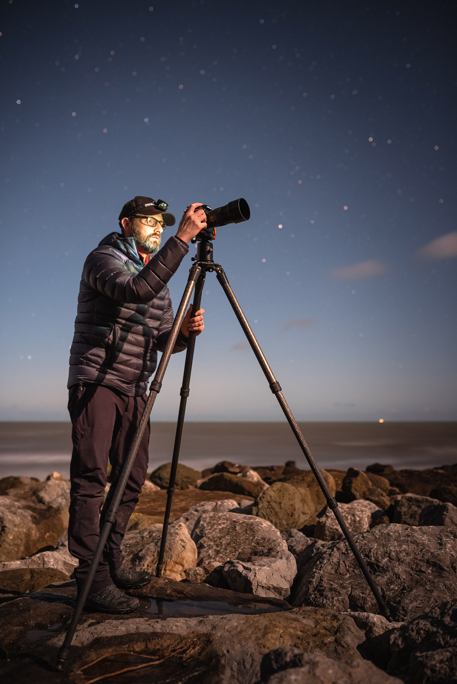 Photographer Ainsley Bennett taking photos with a camera on a tripod at night