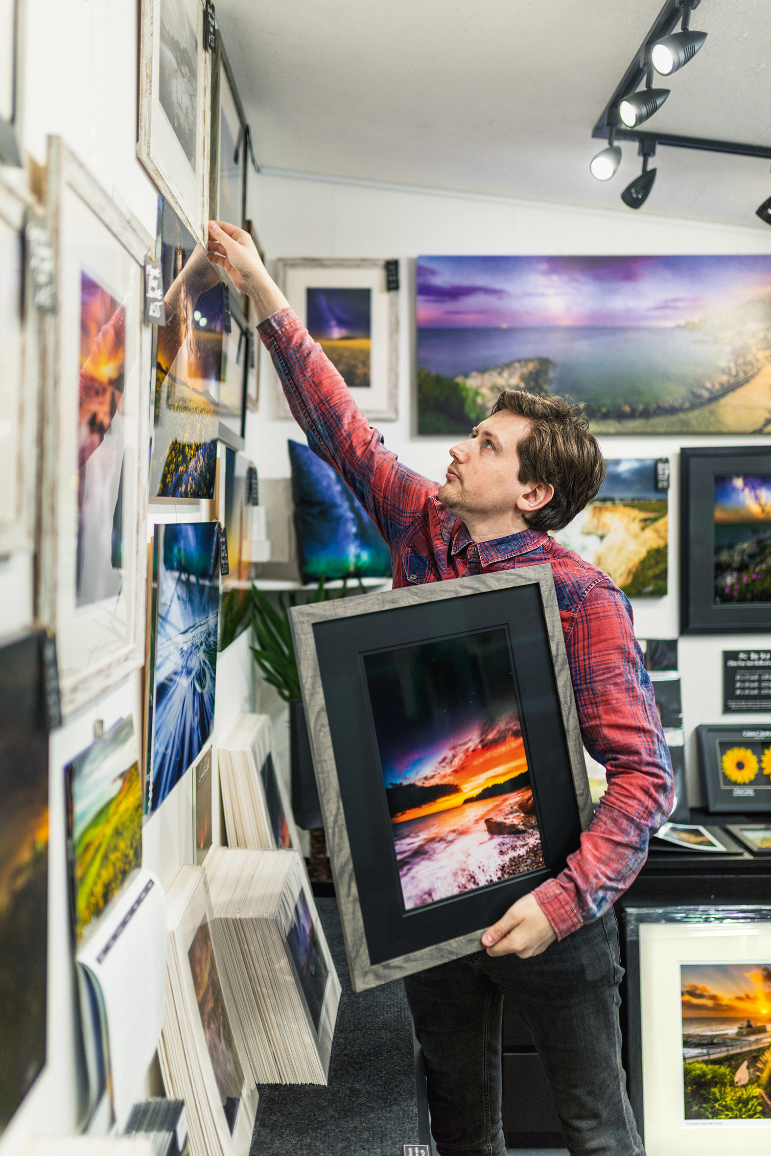 Photographer Chad Powell in his studio on the Isle of Wight hanging pictures