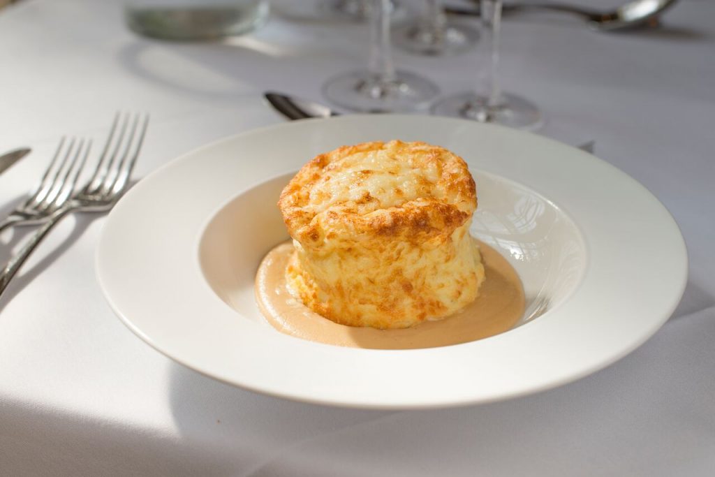 A cheese souffle at a restaurant, pictured with a white plate and tablecloth, made from Isle of Wight Gallybagger cheese