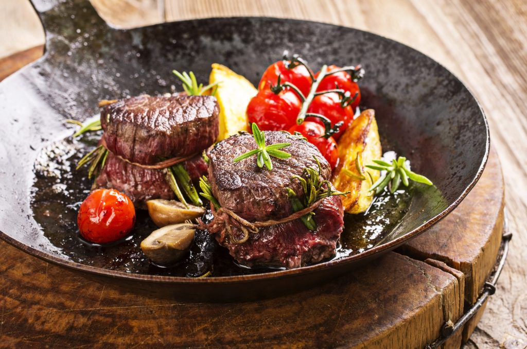 A pan with venison medallions, tomatoes and herbs