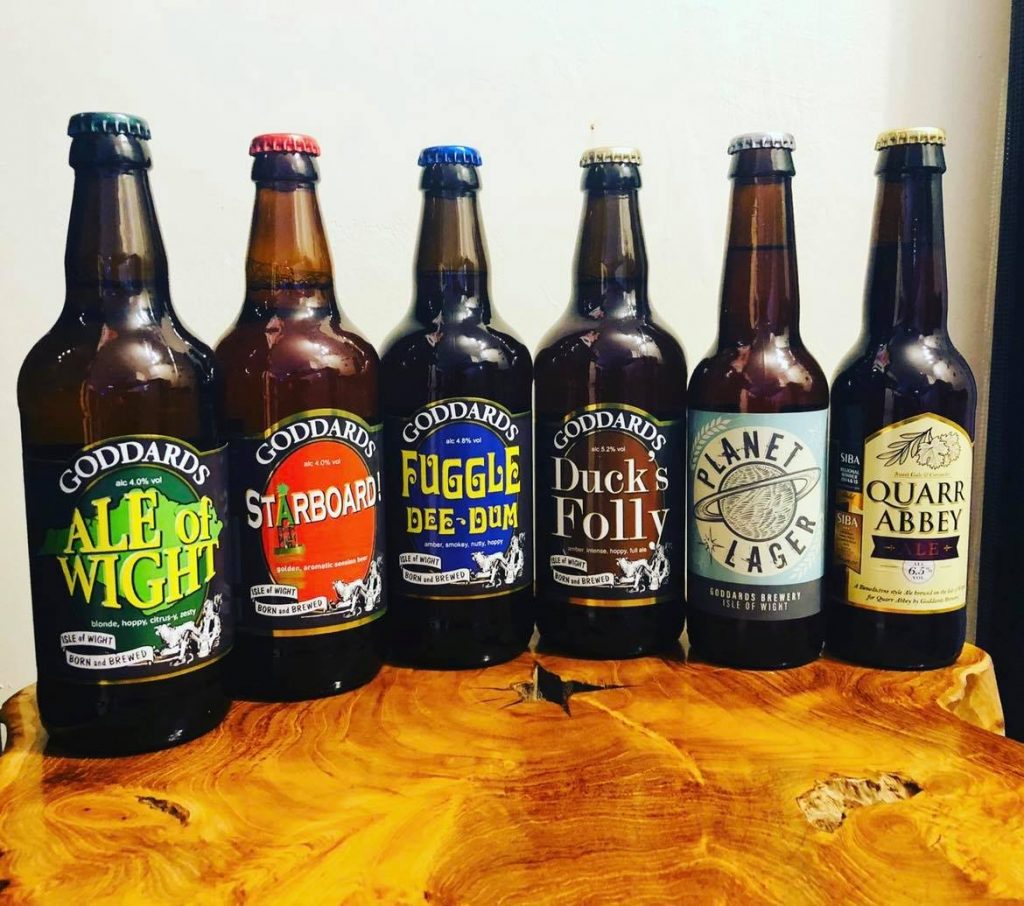 A selection of Goddard's Brewery bottles containing different ales on a wood table