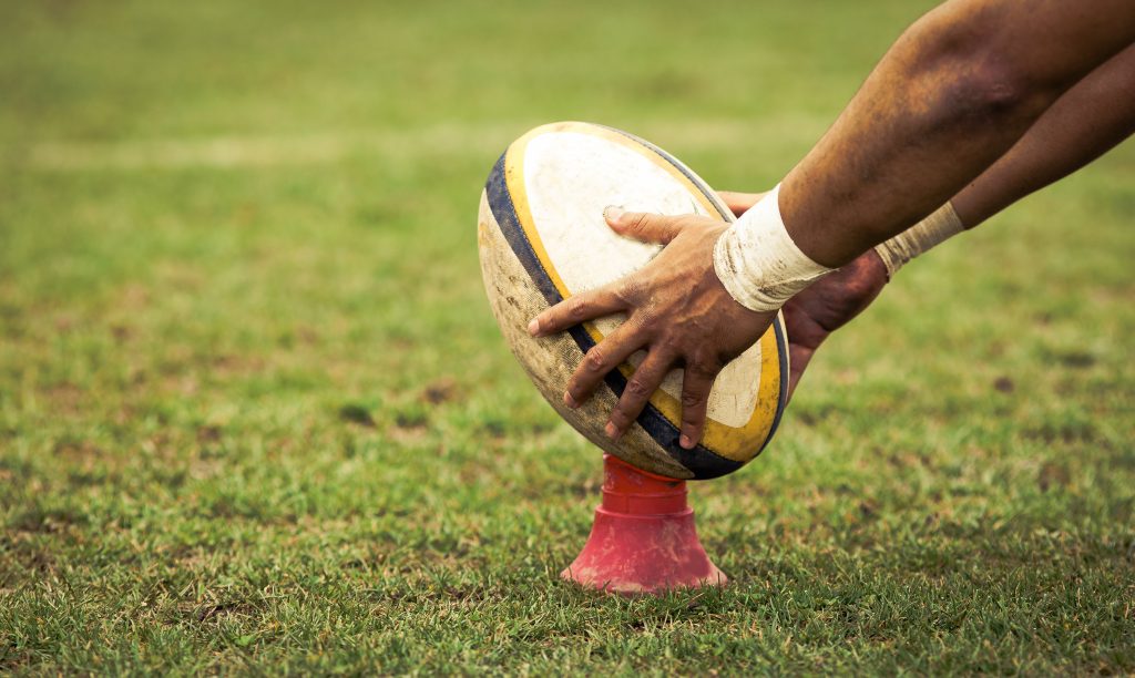 Hands setting up a rugby ball