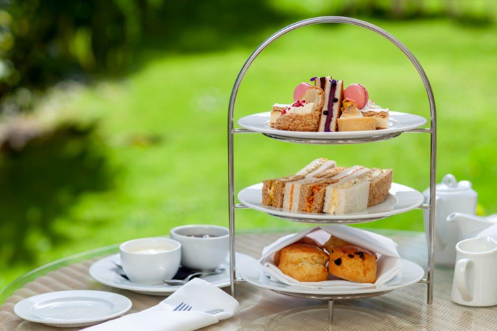 Tiered plates with afternoon tea items on, in a garden on the Isle of Wight