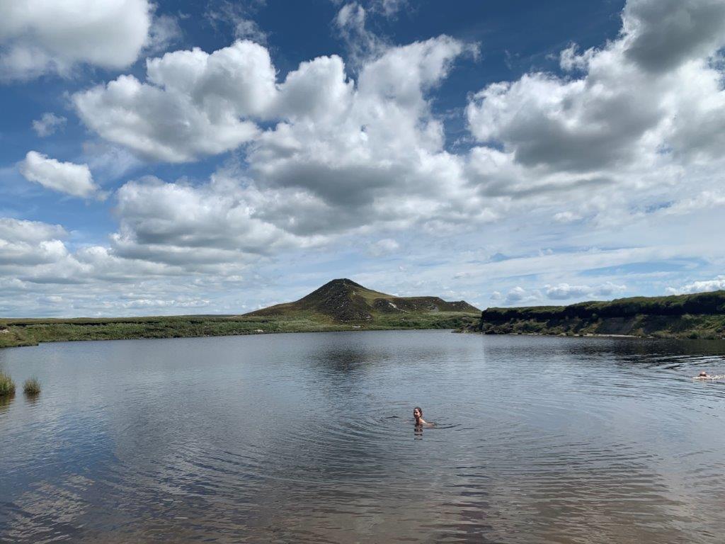 Person wild swimming in a lake in Dartmoor, Devon - Credit Wandering Wild