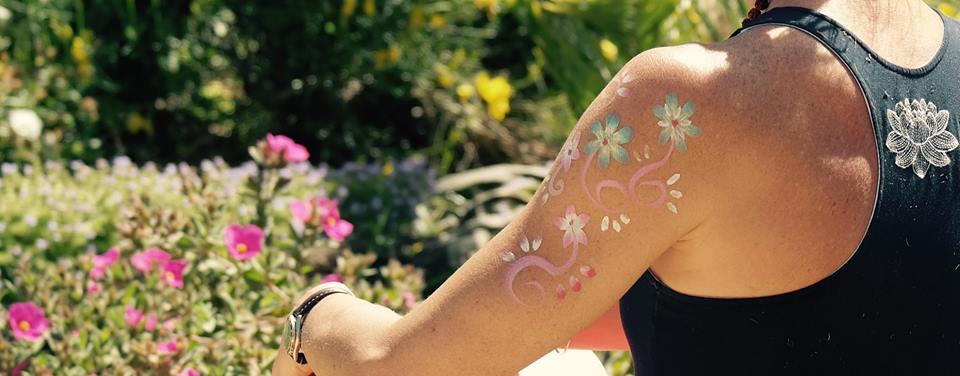A person with flowers drawn on their arm meditating in a garden