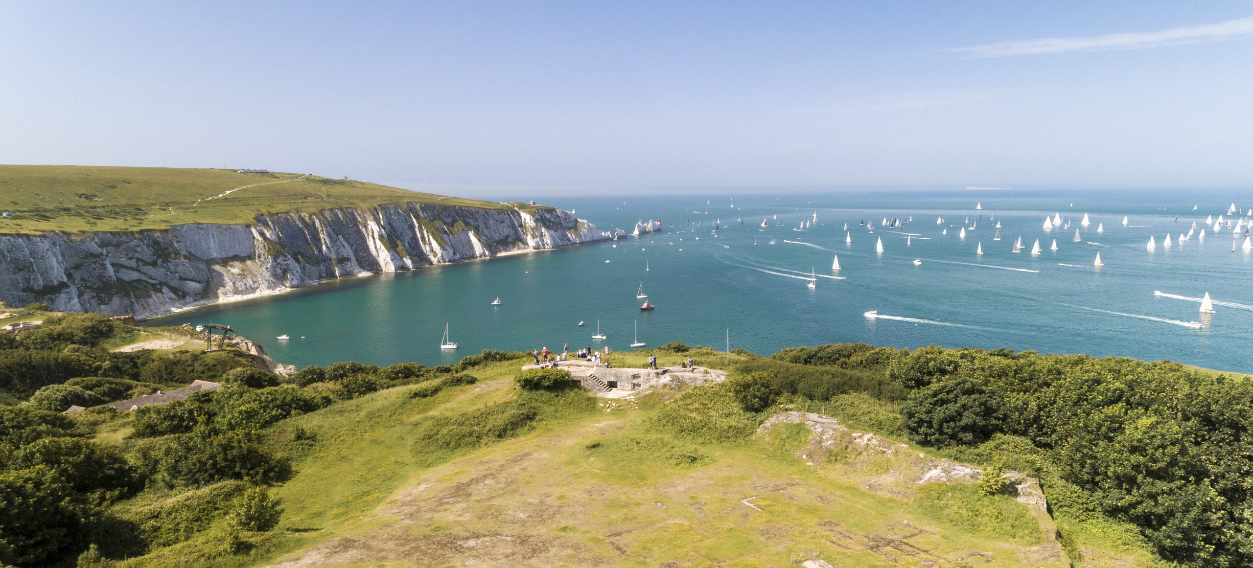 A view across The Needles, Isle of Wight, with many sailing boats in the water and countryside in the foreground