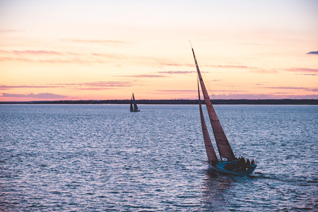 A yacht sailing at sunset on calm waters off the Isle of Wight