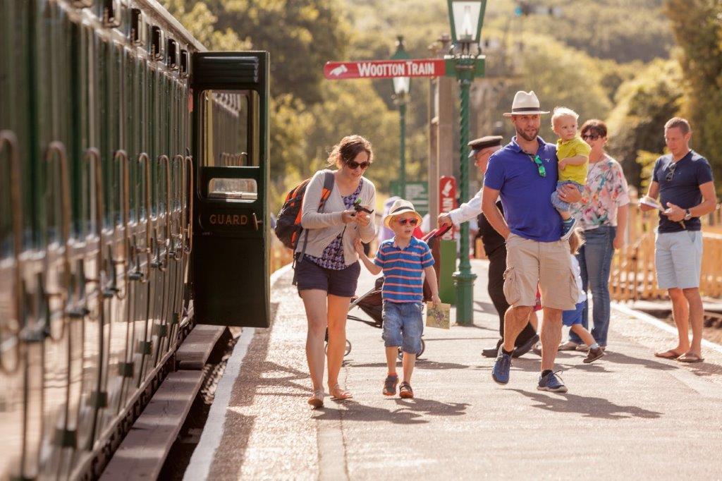 A family on a platform of the Isle of Wight Steam railway next to a steam train
