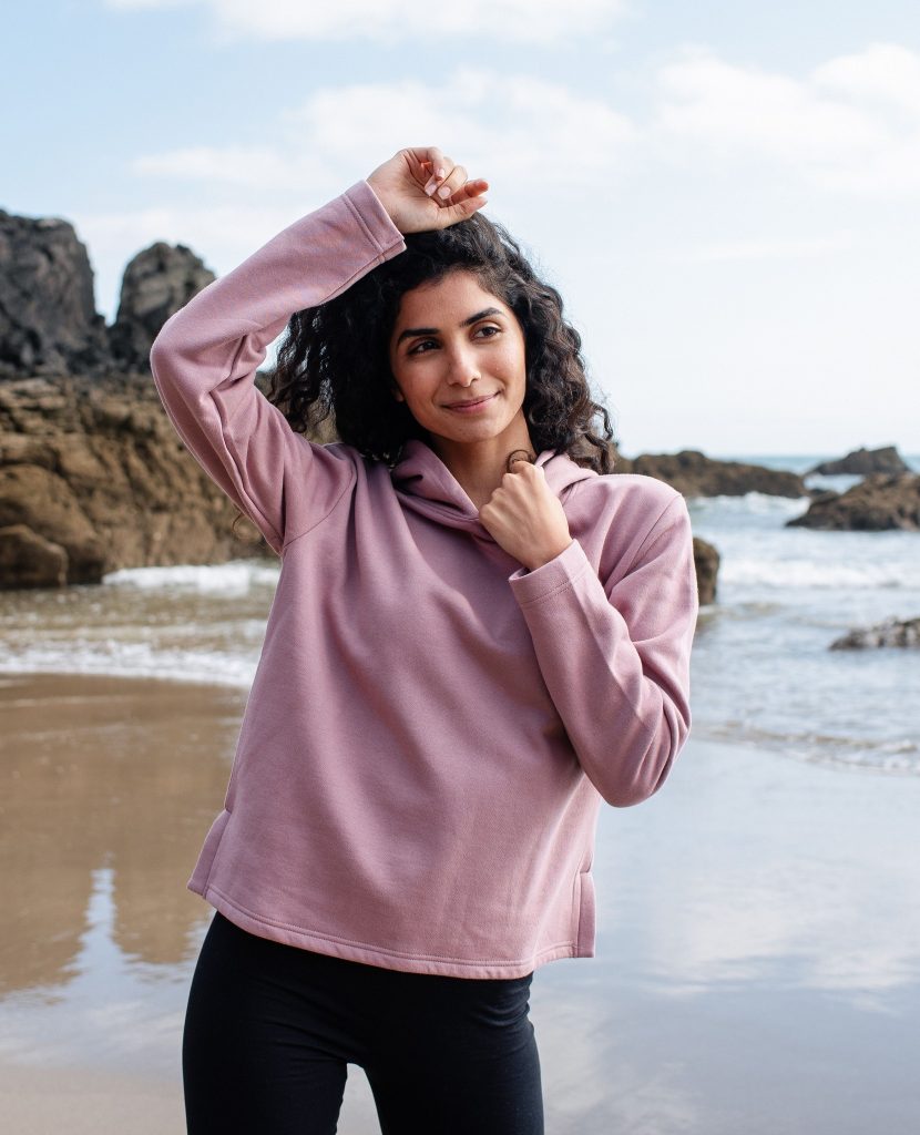 A woman on the beach wearing a pink hooded sweatshirt