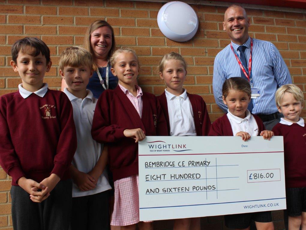 A group of schoolchildren with a teacher and member of Wightlink staff holding a giant grant cheque