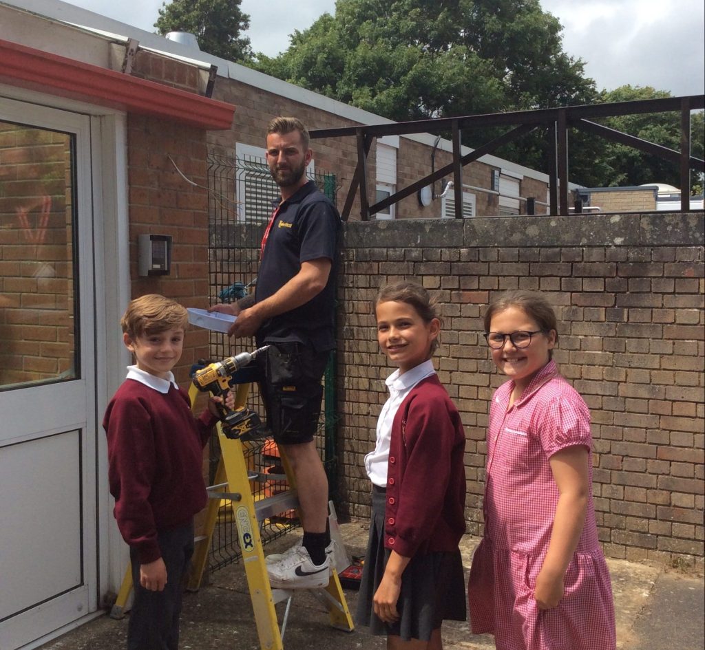 Bembridge School pupils with an engineer from TL electrical fitting energy efficient lights