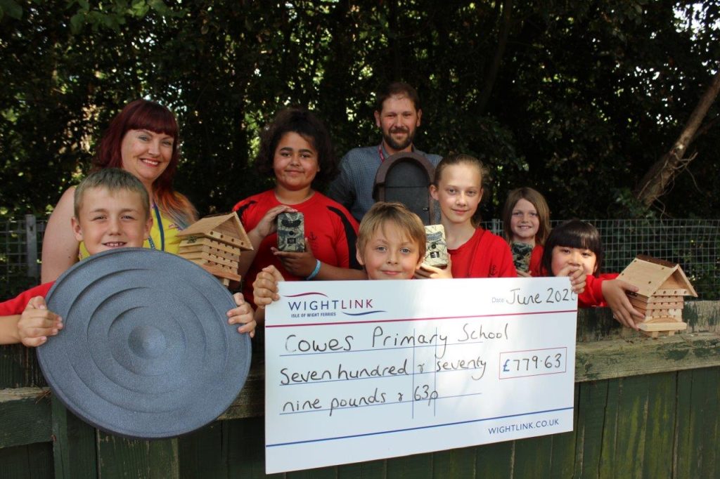 Pupils from Cowes Primary School holding a large cheque and multiple garden items