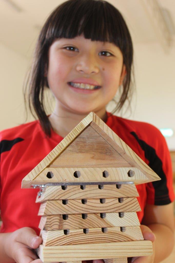 A pupil from Cowes Primary School holding a bug hotel