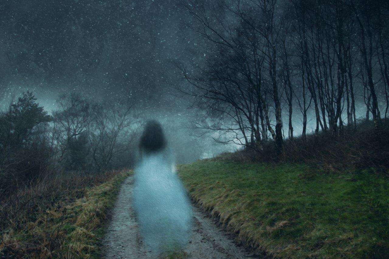 Ghostly female figure walking on a wooded path