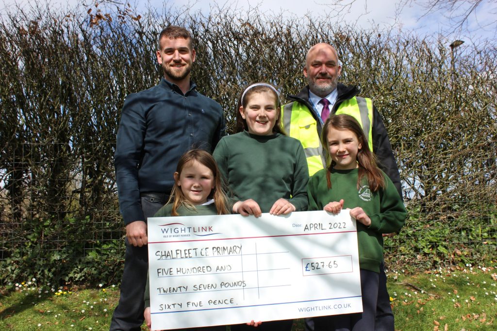 School pupils holding up a giant grant cheque with Wightlink representative and a school teacher with trees in the background