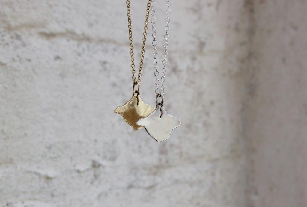 Isle of Wight shaped necklace hanging against a brick wall
