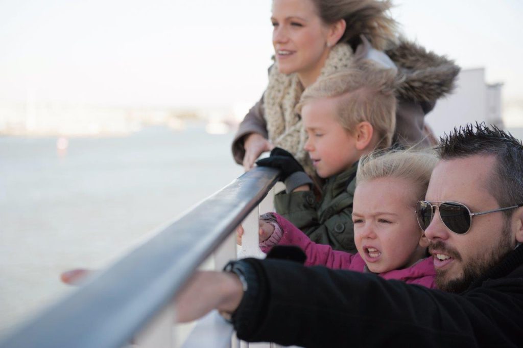 Two adults and two children looking out to sea from a ferry in winter
