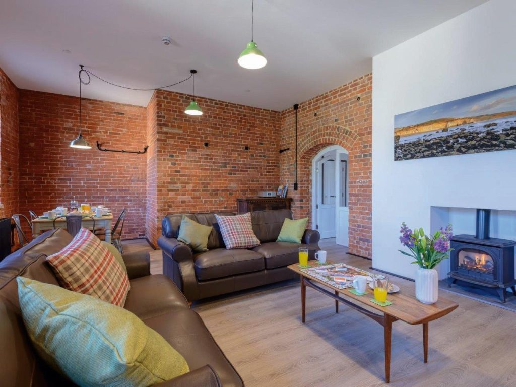 Living room with sofas, wood burner, exposed brick and industrial lighting - at a cottage on the Isle of Wight