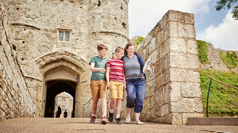 A family of 3 standing at the entrance to Carisbrooke Castle on the Isle of Wight