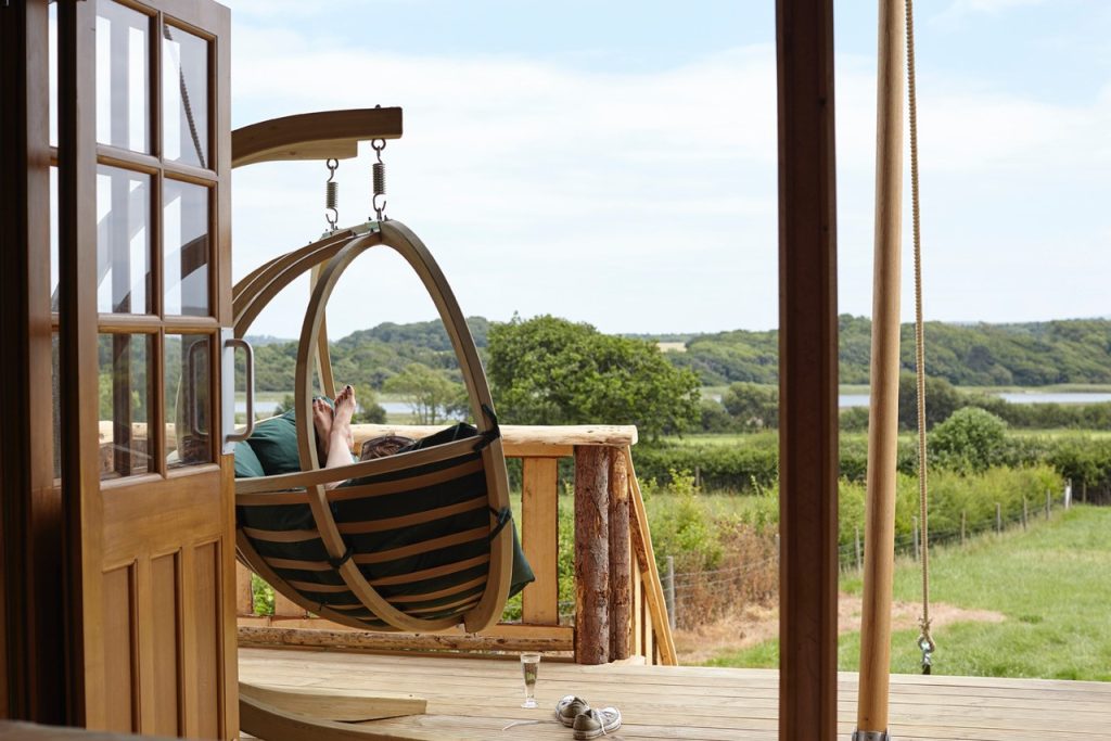 A holiday-goer relaxes in a swinging chair outside a glamping tent on the Isle of Wight