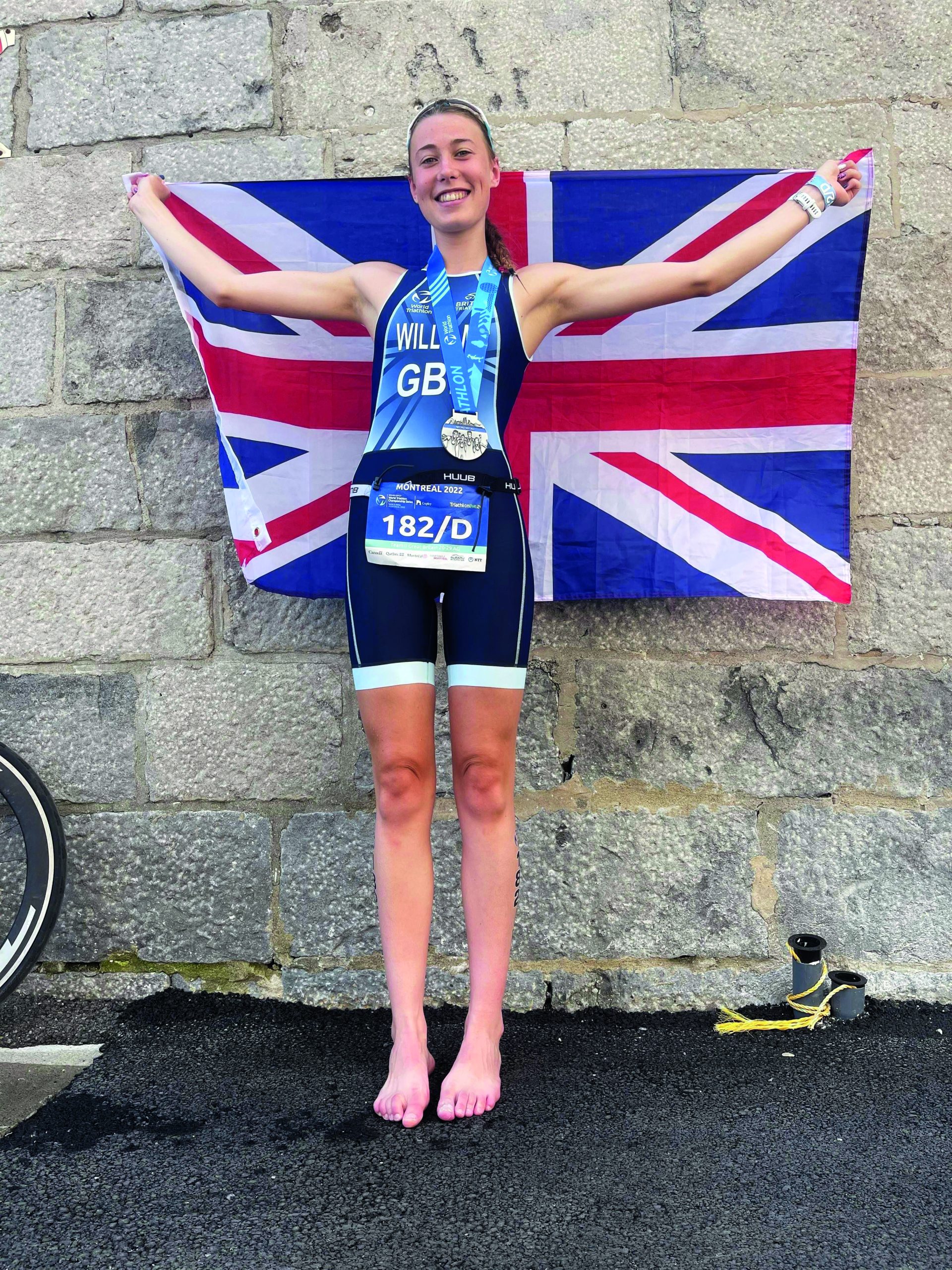 Island Triathlete Millie Williams in Canada, holding a GB flag