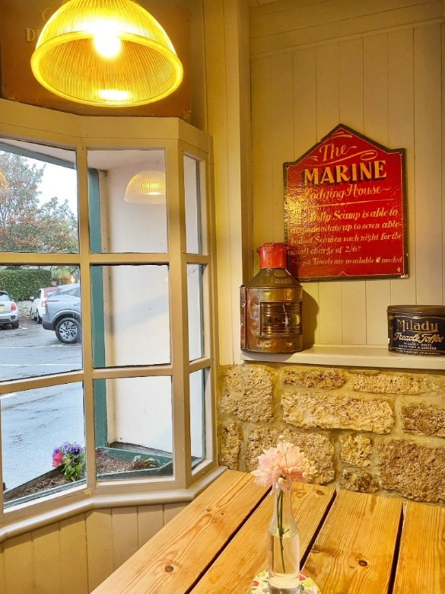 A wood table inside a pub, next to a window. There's a light on and signage on the wall