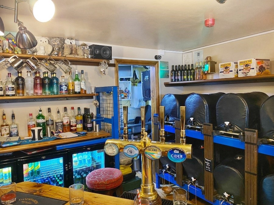 Inside a bar called the Ale House, fridges, bar taps and bottles are shown
