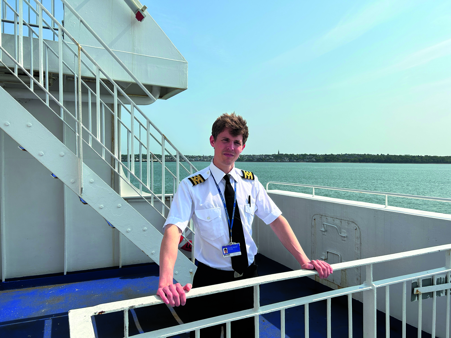 A man in a chief officer's uniform standing on the deck of a ferry at sea