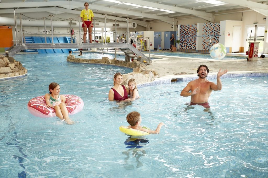A family play with inflatable pool toys inside Nodes Point Holiday Park's indoor pool