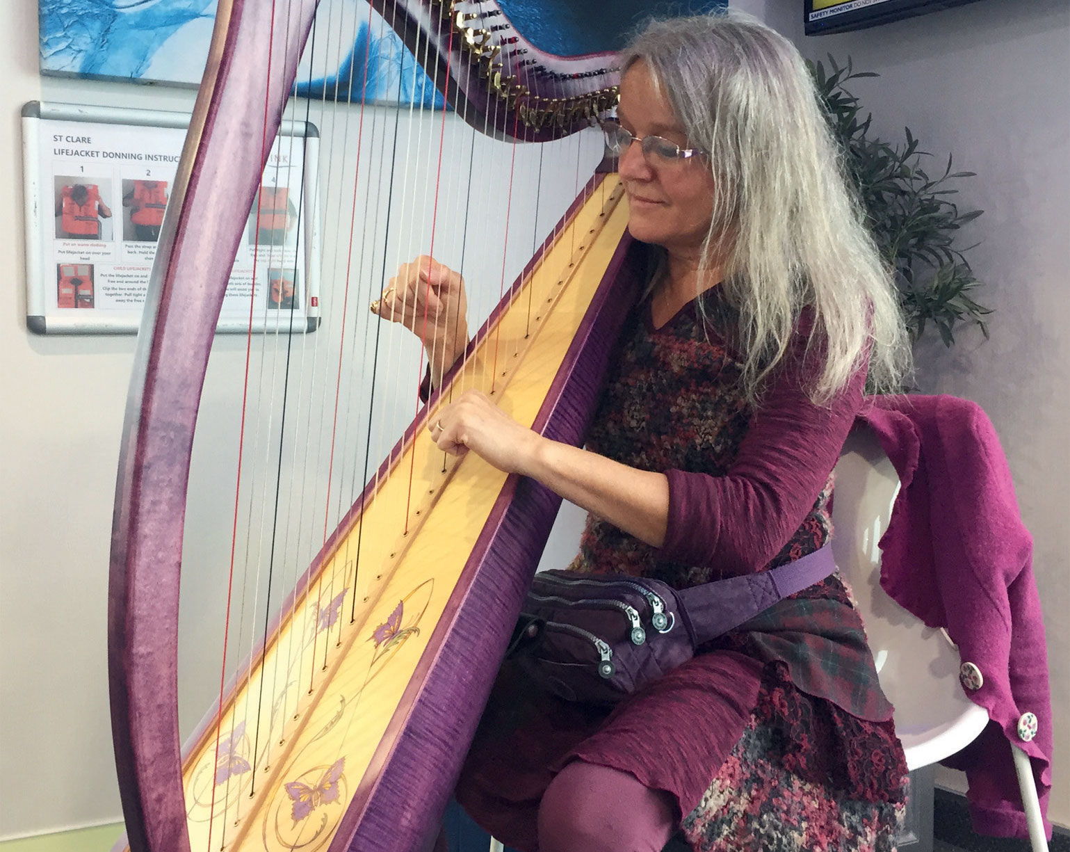 A woman wearing purple playing a harp indoors