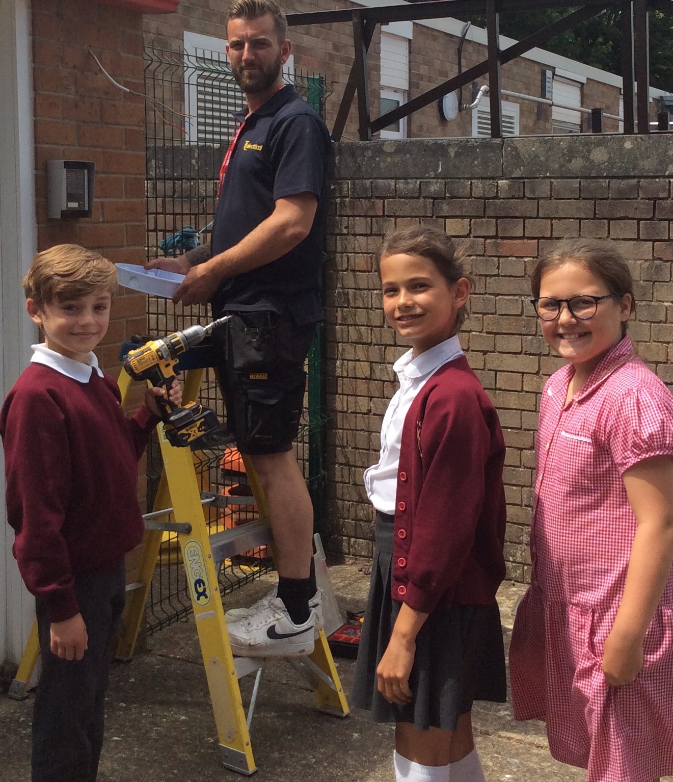 Three school children help fit low-energy lights fitted with motion sensors are installed at Bembridge Primary on the Isle of Wight