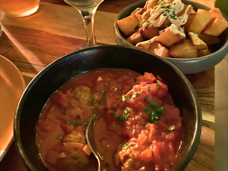A tapas dish with tomatoes and a dish of patatas bravas potatoes