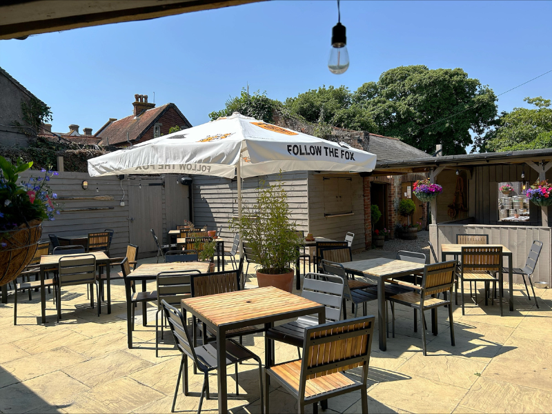 A patioed garden with tables and chairs, it belongs to a pub on the Isle of Wight