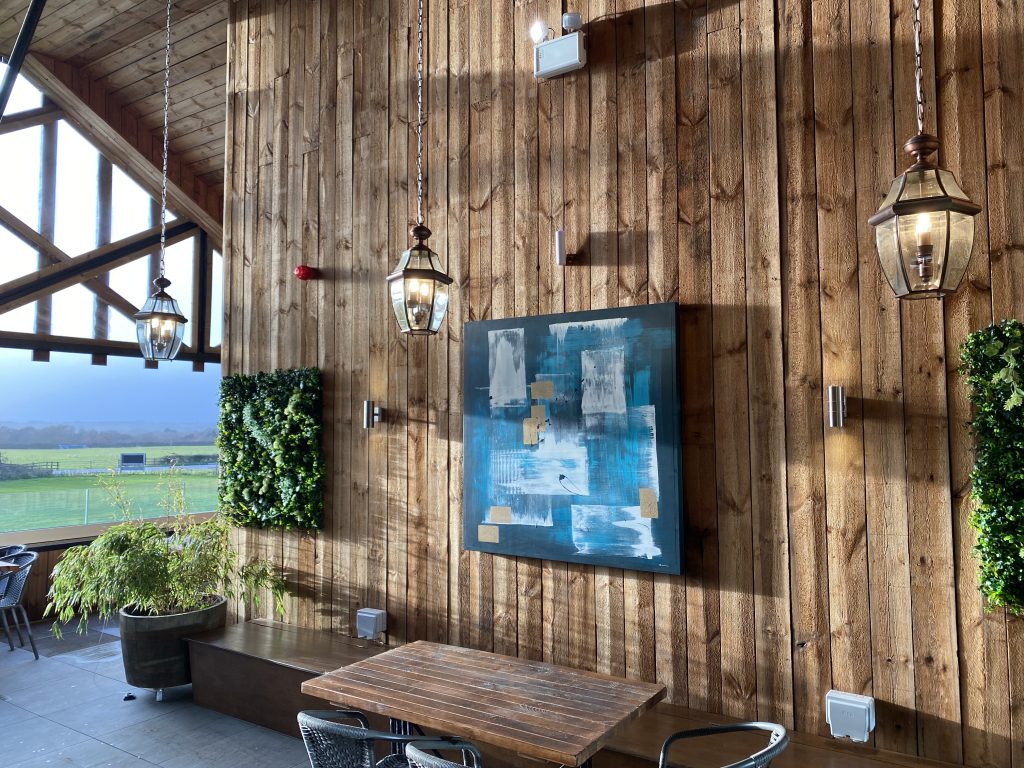 A modern interior of a brewery visitor attraction, with wood panelling, seating and views over the countryside