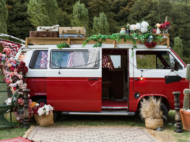 A red Volkswagen campercan decorated with floral displays and lights