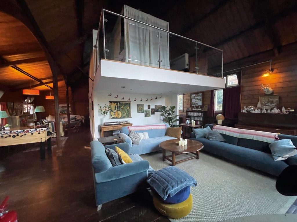 Inside a converted Victorian chapel made from corrugated tin. The interior photo shows a mezzanine and lounge area, it's cosy and eclectic.