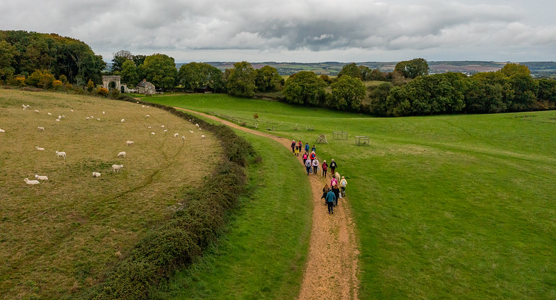 A group take a guided walk along a stoney path between two fields on the Isle of Wight