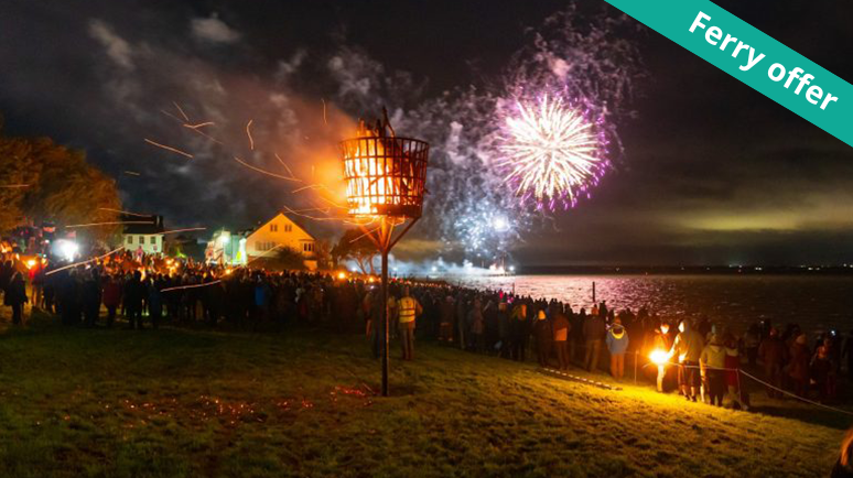 A large crowd gathered in Yarmouth Isle of Wight watching fireworks over the bay. A green banner is in the top right and reads 'ferry offer'