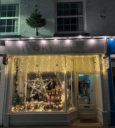 The front of a hair salon window, it's called Ivory and there are lots of Christmas decorations and lights in the window display