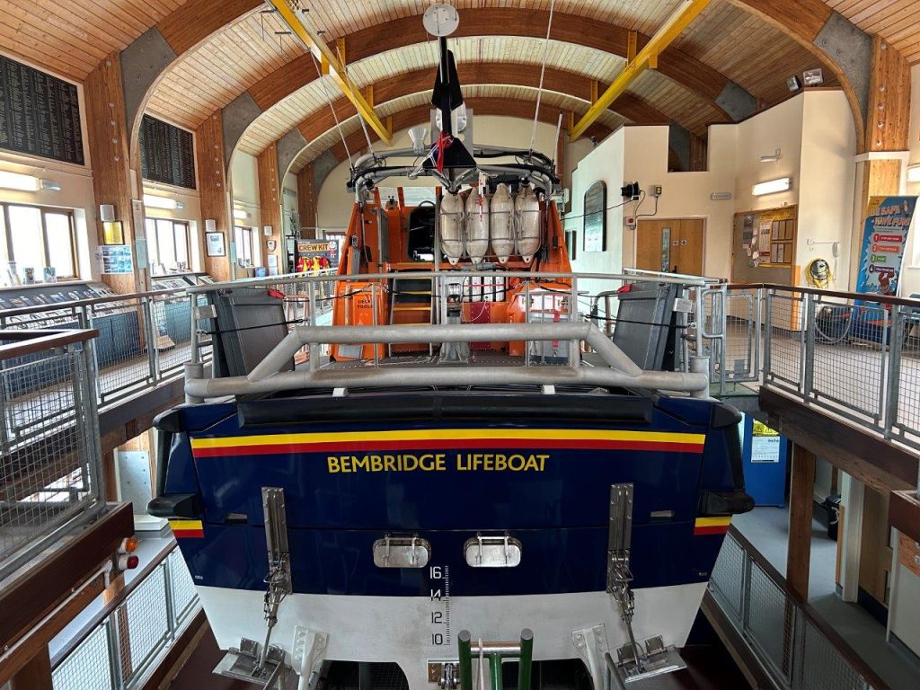 A lifeboat inside a vaulted lifeboat station, it says "Bembridge Lifeboat" on it.