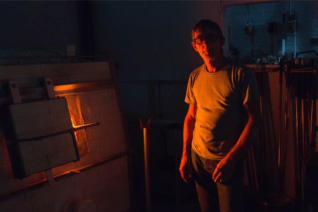 A man standing in a dimly lit room next to a furnace