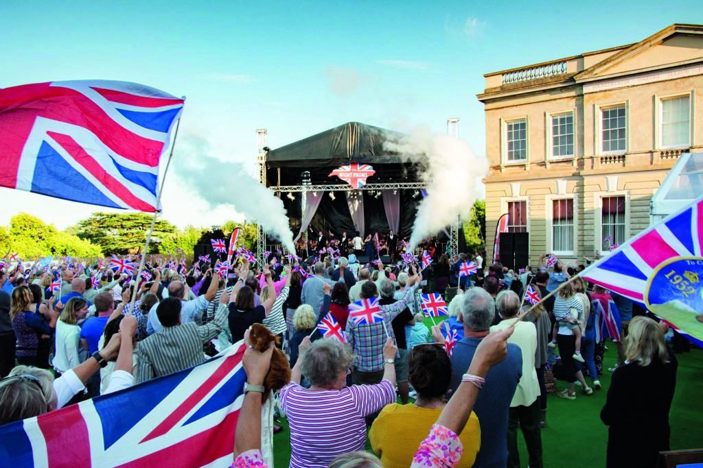A crowd at a small music event waving Union Jack flags