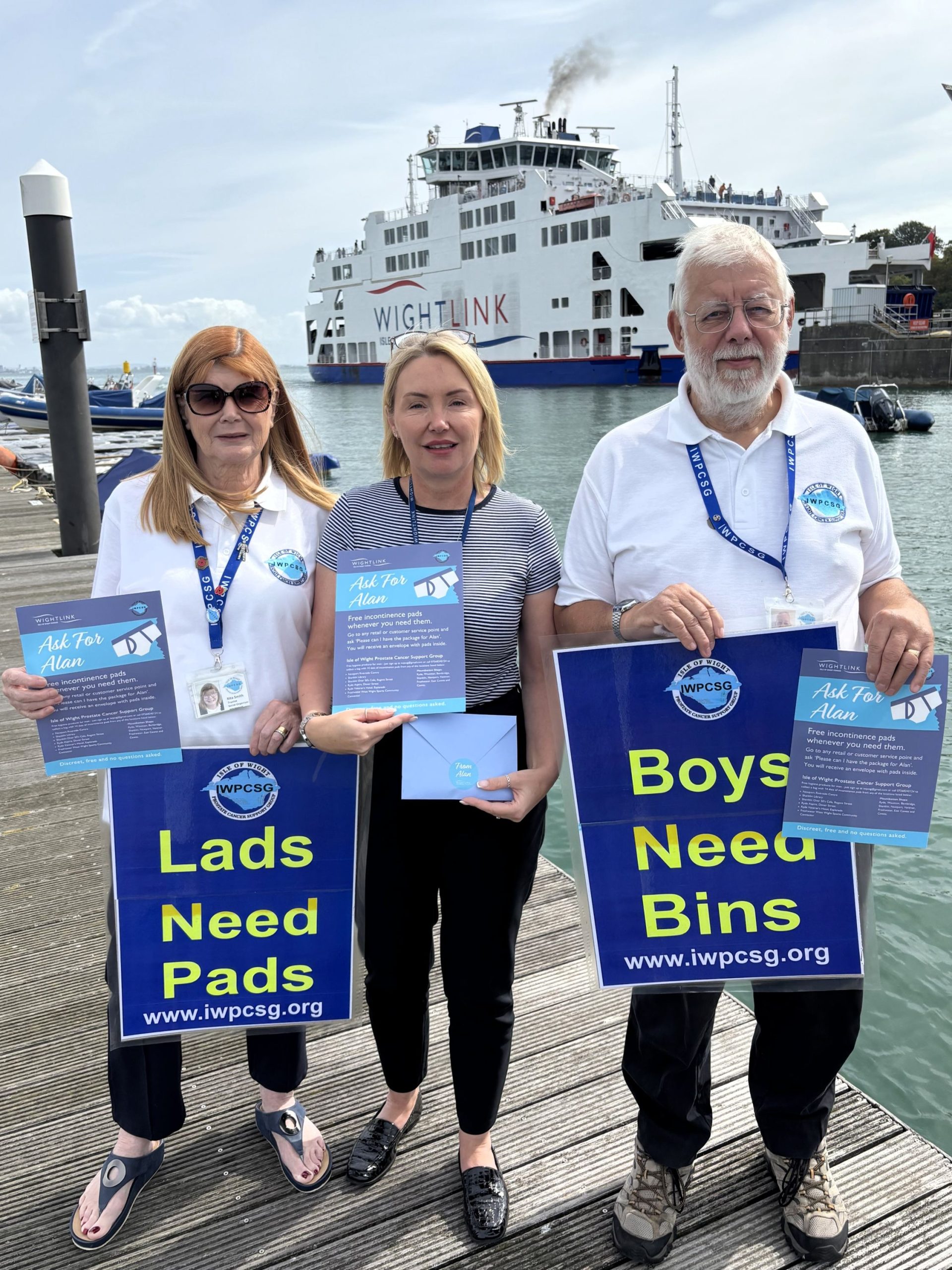 A man and two women stand in front of a ferry holding signs