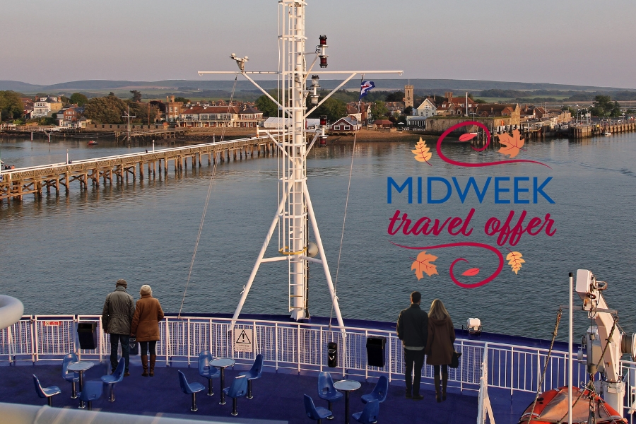 Two couples standing on the sun deck of a Wightlink ferry as it approaches Yarmouth harbour on a calm autumn evening, enjoying clear views of the pier and village.